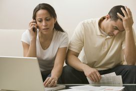 一个烦恼夫妇坐在沙发上,无奈持续债权人破产后的电话。”width=