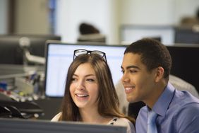 大学生们在暑期打工的办公室里一起看着电脑屏幕。