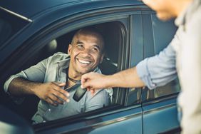 一个司机借了一辆车，微笑着从窗口接过钥匙