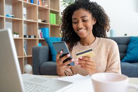快乐的年轻黑人妇女使用信用卡在家里