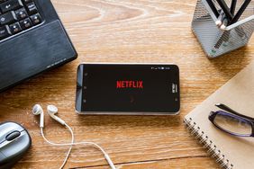 木桌上的智能手机屏幕上播放着Netflix流媒体