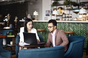 Man and woman working on a laptop at a coffee shop