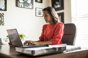 女人在红衫军坐在桌子放在一个家庭办公室笔记本电脑上打字。”>
          </noscript>
         </div>
        </div>
       </div>
       <div class=