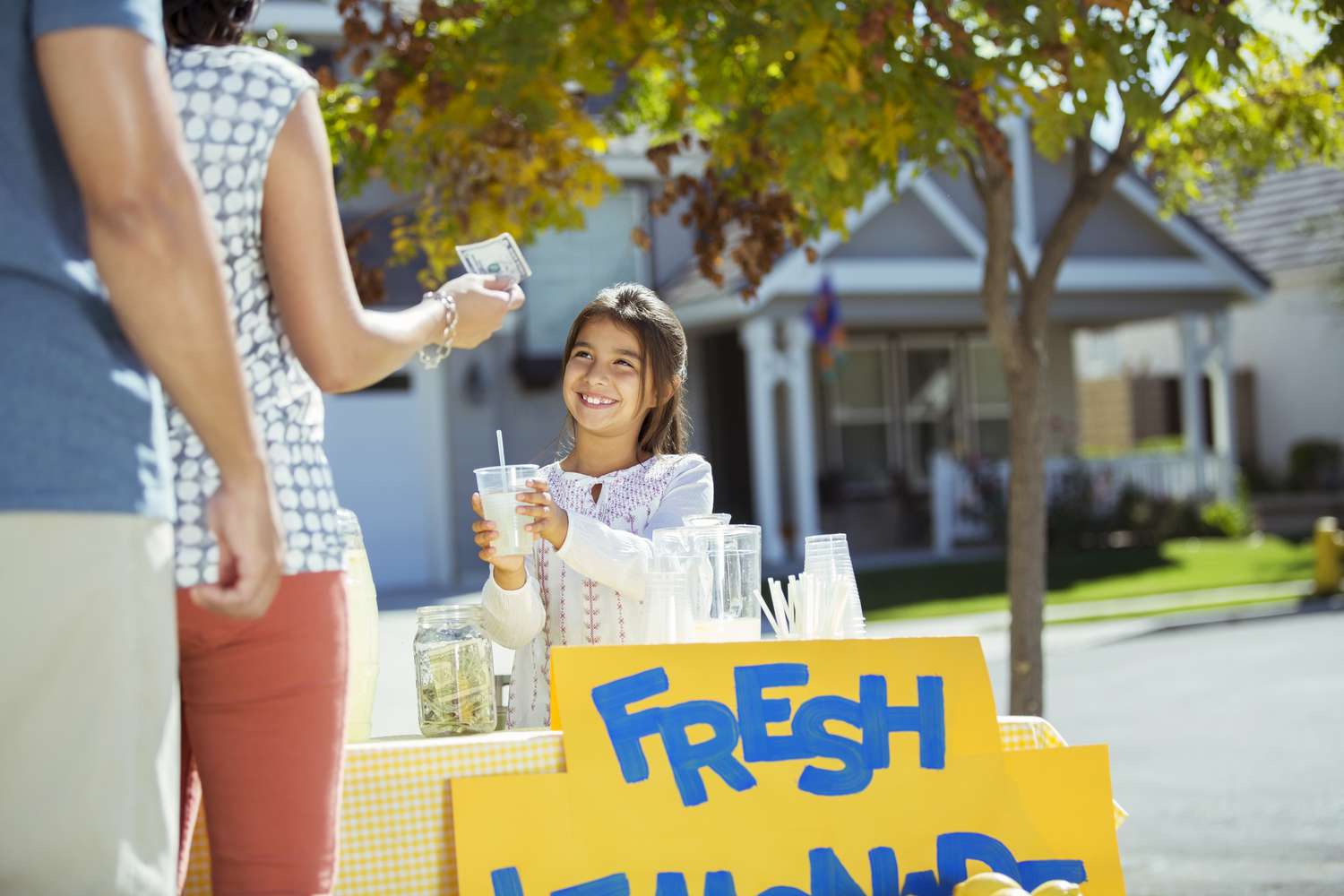 一个小女孩在她前院的柠檬水摊上买一杯柠檬水只拿了一美元。