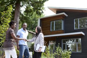 Real estate agent greeting couple at house