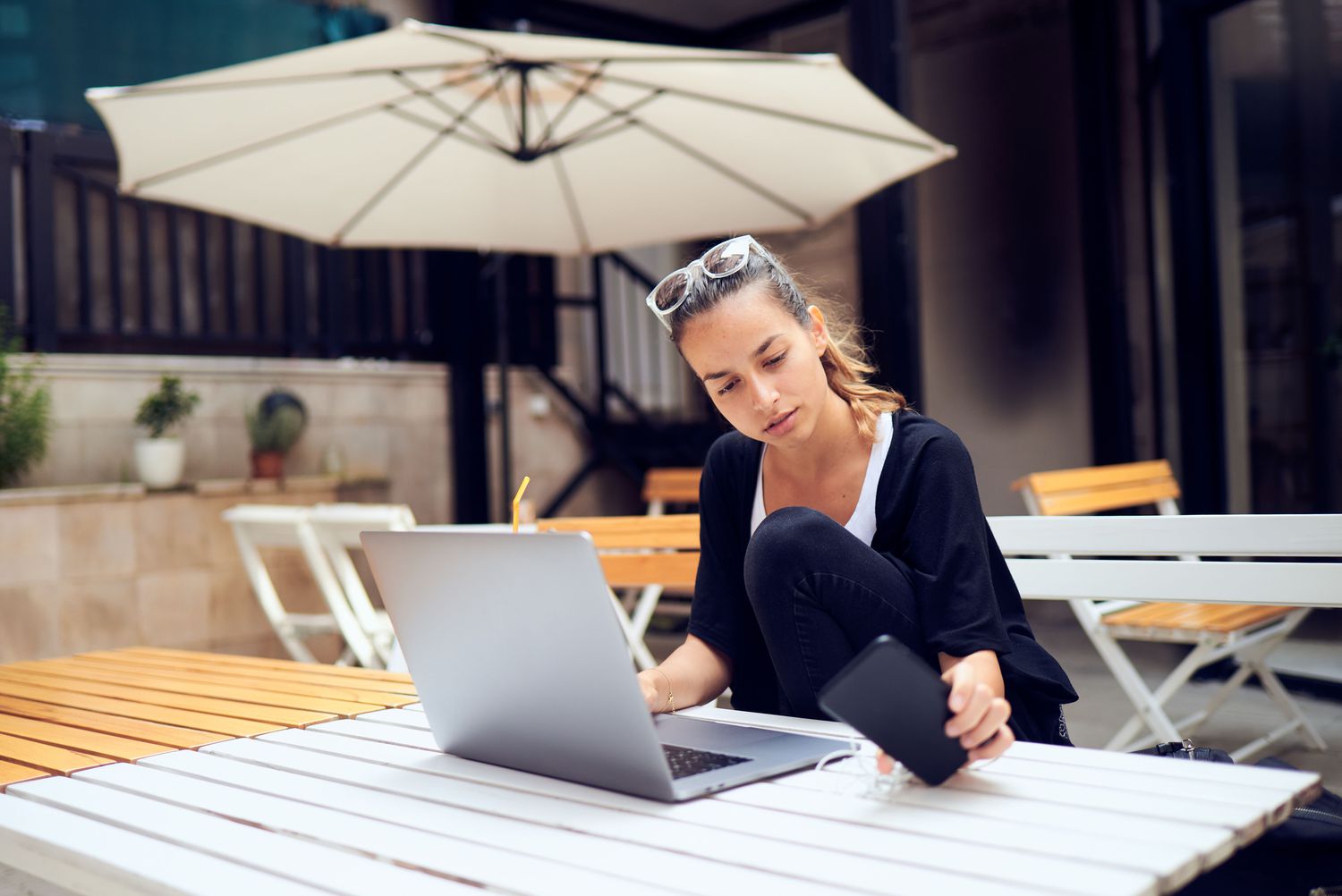 图像显示一个女人坐在阳台工作在她的笔记本电脑。”class=