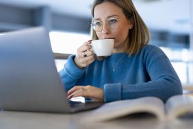 一位女士在电脑前喝茶。