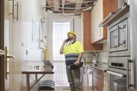 An inspector surveys a damaged ceiling in a kitchen.