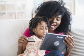 母亲拿着信用卡和女儿看数字平板电脑