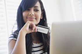 一个拿着信用卡的女人看着电脑