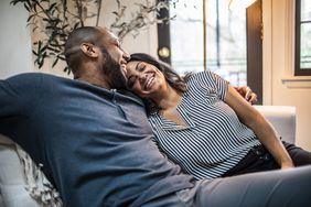 Spouses sit on a couch together.