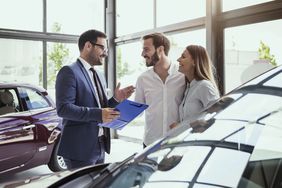 一对夫妇与汽车销售员交谈。