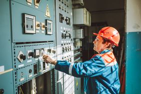 一位高级妇女，工程技术员，在电力调度站操作复杂的设备，检查系统状态，调整电网参数。