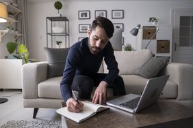 一名男子在咖啡桌上完成文书工作，旁边有一台笔记本电脑。＂>
          </noscript>
         </div>
        </div>
       </div>
       <div class=