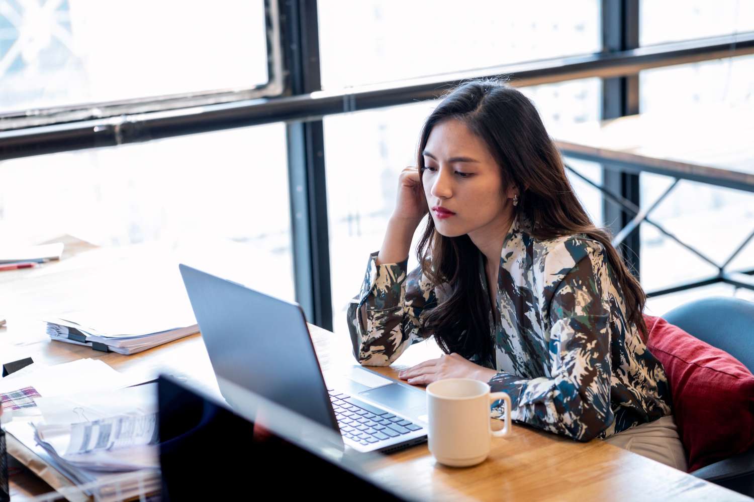 年轻的女商人喝咖啡在办公室查阅笔记本电脑