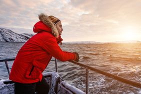 冬天的北极，一名穿着红色夹克的男子在船上