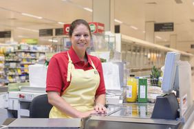 微笑的女人的肖像在杂货店结账工作