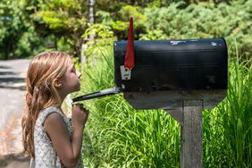 一个女孩在户外看一个乡村邮箱