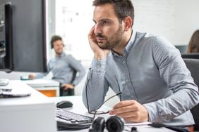 一名男子坐在办公室工作的地方，盯着电脑屏幕，戴着眼镜。＂>
          </noscript>
         </div>
        </div>
       </div>
       <div class=