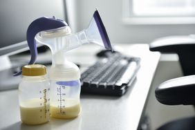 一台吸奶器和一瓶母乳放在电脑旁边