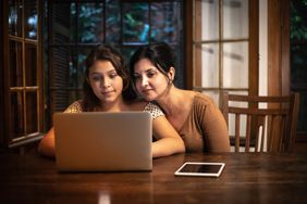 妈妈和女儿坐在木桌上看电脑