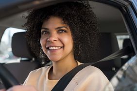 微笑的女人开车，看着窗外