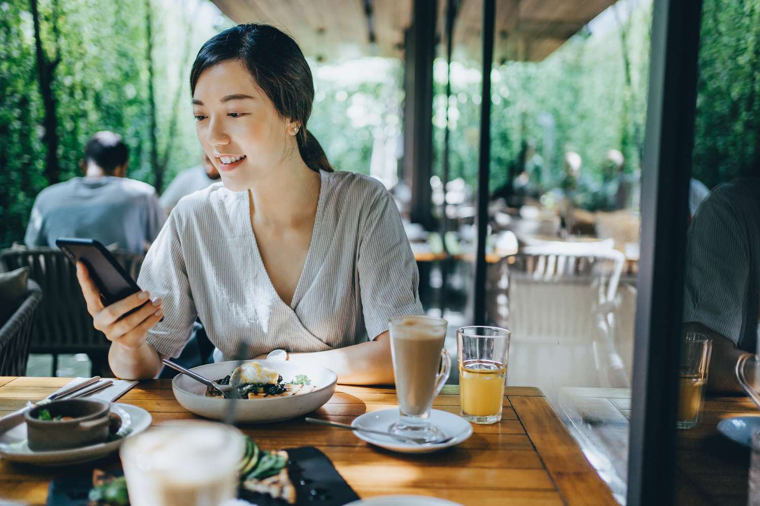 一位女士在吃饭时用手机。