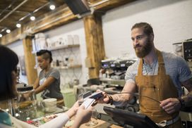 Customer paying barista with credit card in cafe