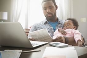 一位父亲抱着他的宝贝女儿，担心地看着银行对账单