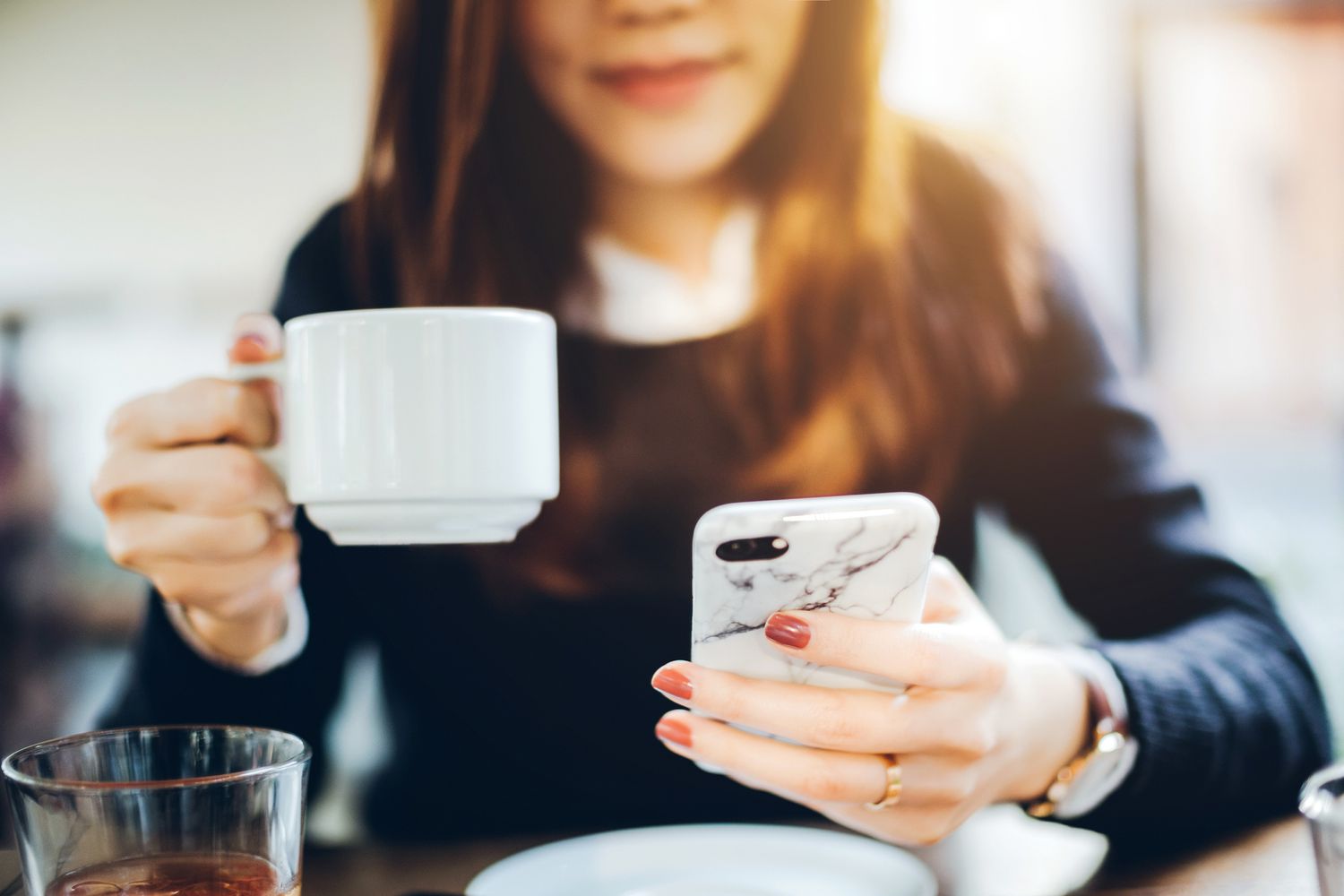 女人拿着iphone和一杯咖啡