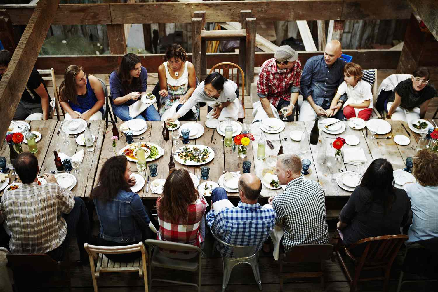 一群人聚集在公共生活领域的餐桌上分享一顿饭”class=