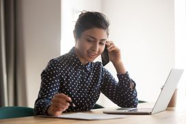 忙碌的印度女员工在办公室用智能手机聊天，在纸上写文件，千禧一代的少数民族女员工用手机咨询客户，用笔记本电脑在文件上手写＂width=