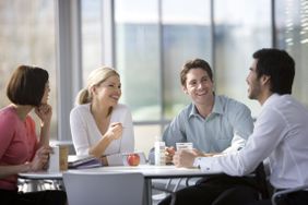 四个同事在午餐或休息时间在办公室食堂聊天