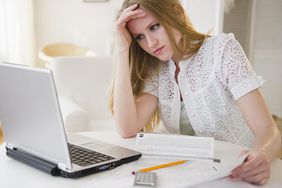 年轻女子在桌子上用笔记本电脑做贷款文书工作