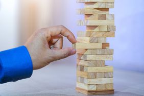 叠叠游戏中的手拆积木象征着商业中的计划、风险和策略