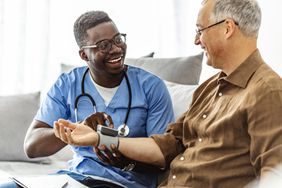 African-American male nurse measuring blood pressure of mature patient
