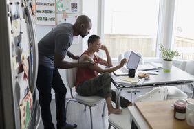 Couple looking at bills together in their kitchen using a laptop