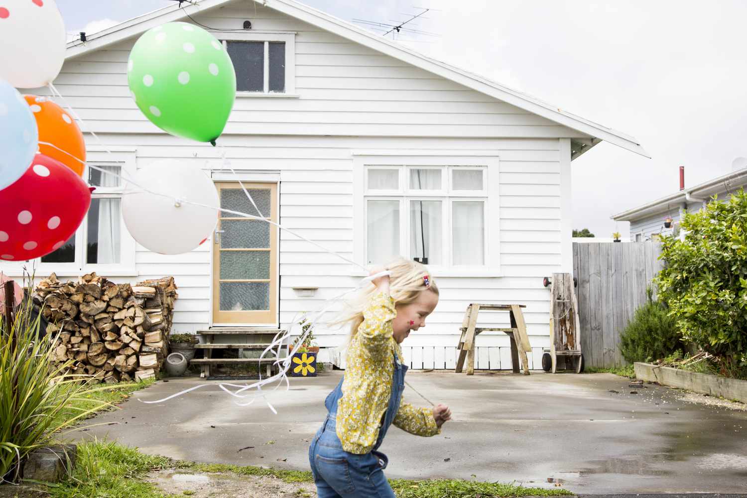 一个孩子拿着气球在房子前奔跑