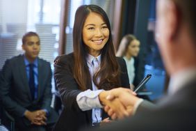 年轻女子与人握手，其他人在后台等待