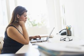 女人黑色衬衫计算机在明亮的房间里工作”width=