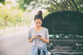 年轻女子在车附近的手机打开引擎盖