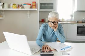 女人在厨房桌子上用笔记本电脑和计算器工作