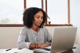 年轻女孩戴着耳机在电脑上工作
