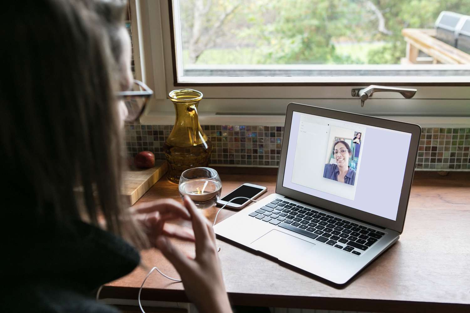 高角度视角的女商人视频打电话给女同事在笔记本电脑在家庭办公室