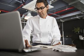 身着制服的厨师在工业餐厅厨房使用笔记本电脑