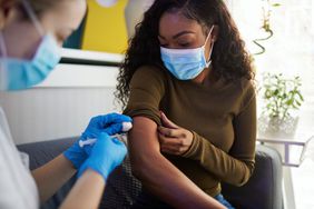 挽起袖子的妇女在护士那里接种疫苗