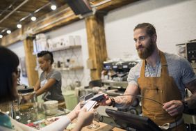 客户用信用卡支付咖啡师在咖啡馆