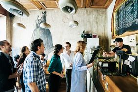 People waiting in line to order food in a busy, trendy burger restaurant.