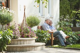 一对老夫妇坐在房子外面的花园里。