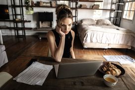 女人在家庭工作室用笔记本电脑工作，有糕点和咖啡＂width=